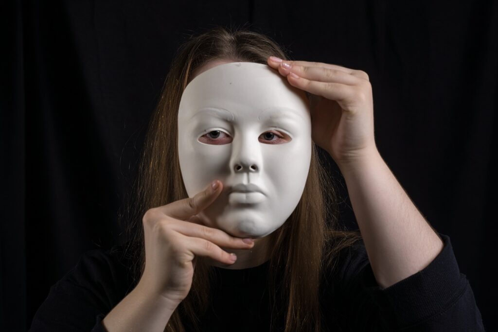 woman holding mask up to her face showing neuruodivergent masking