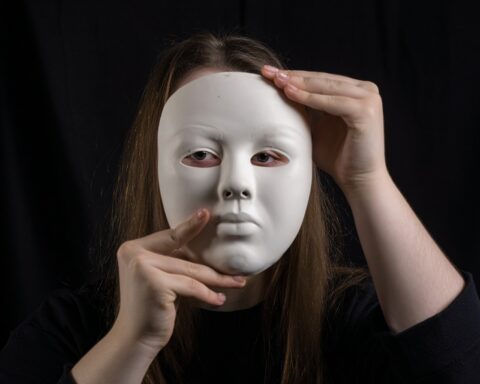 woman holding mask up to her face showing neuruodivergent masking