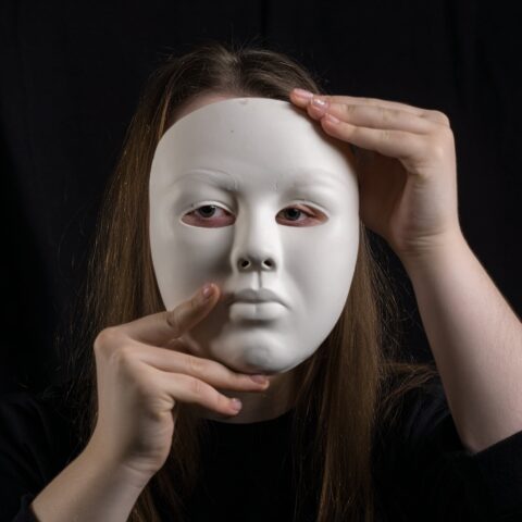 woman holding mask up to her face showing neuruodivergent masking