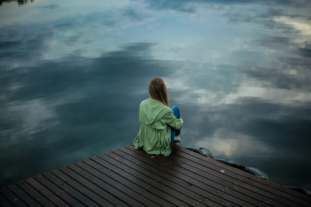 woman sitting on ledge thinking Why Do I Self-Sabotage Even When Things Are Going Well